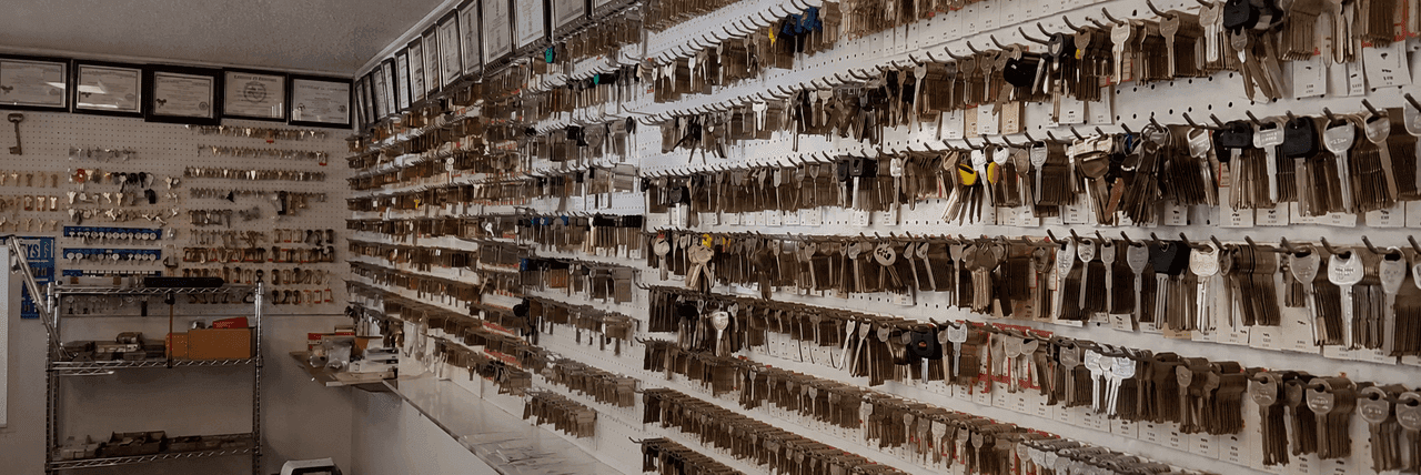 Wall of hundreds of labeled key blanks and locksmith licenses inside Bills Lock and Key shop in Marble Falls, TX